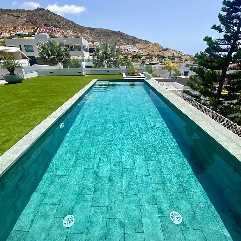 Color que adquiere el agua con cada porcel&aacute;nico en una piscina alargada con c&eacute;sped artificial alrededor