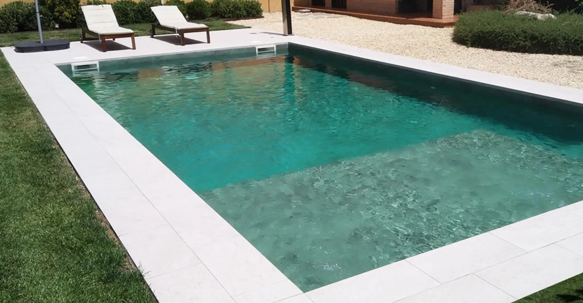 Piscina rectangular con tumbonas y porcelanico para piscinas en un jardín privado Piscina rectangular con tumbonas y porcelanico para piscinas en un jardín privado