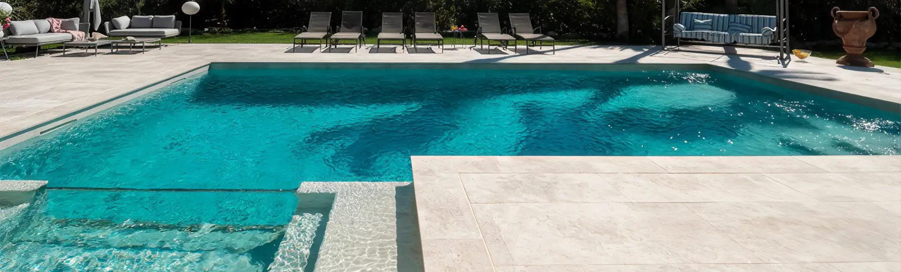 Materiales para bordes de piscinas en tono claro, con acabado continuo entre coronaci&oacute;n y terraza junto al vaso turquesa
